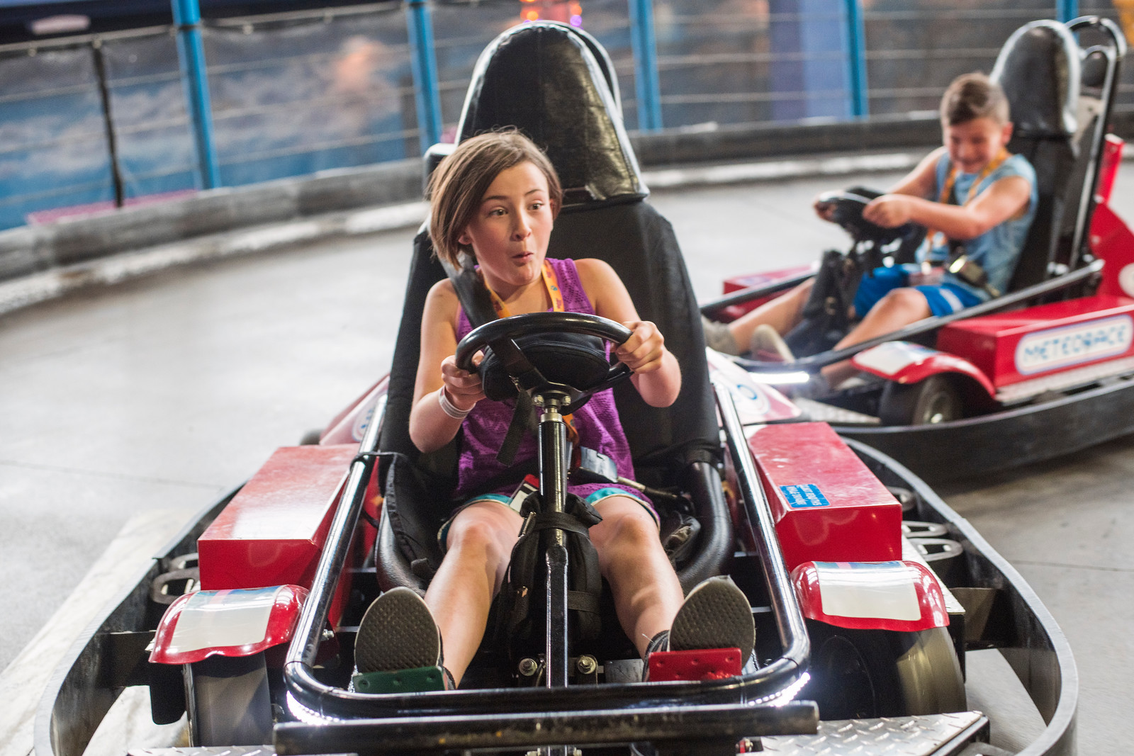 A girl and boy having fun racing around the Meteorace go cart track.