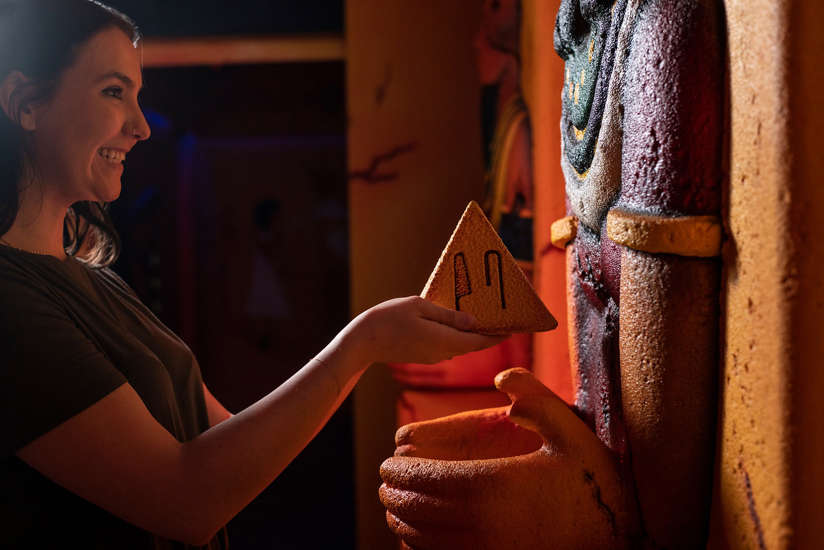 A young lady interacting with an object in the Wrath of Anubis Escape Room.